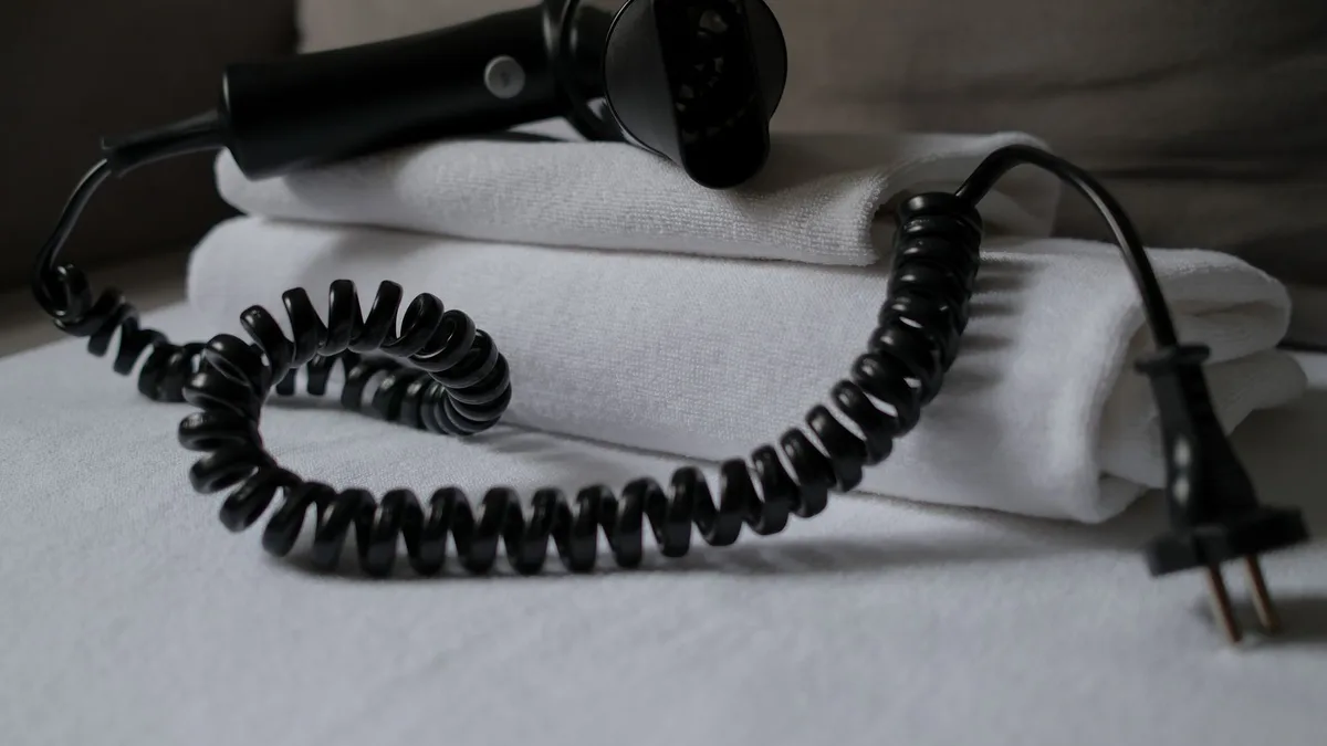 A coiled hair dryer placed on folded white towels, suggesting a hotel setting.