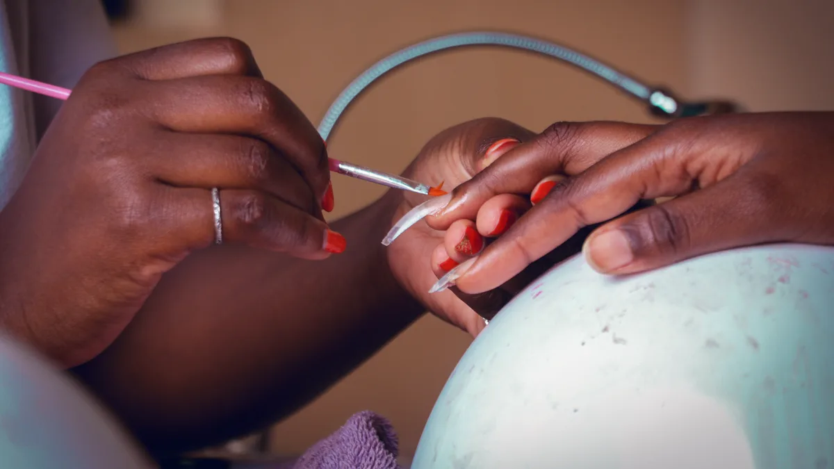 Detailed view of a nail technician applying polish during a manicure session.